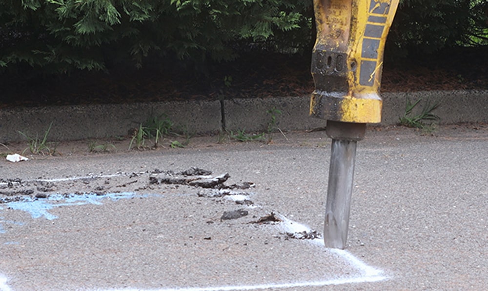 Jackhammer being used to remove section of asphalt